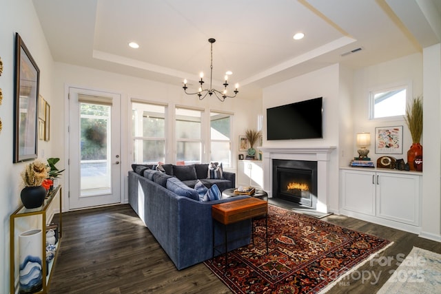 living room featuring dark hardwood / wood-style floors, a tray ceiling, and a notable chandelier