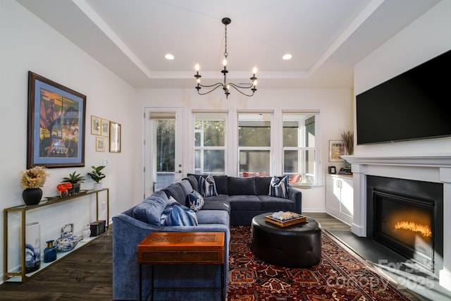 living room featuring dark wood-type flooring, a tray ceiling, and a chandelier