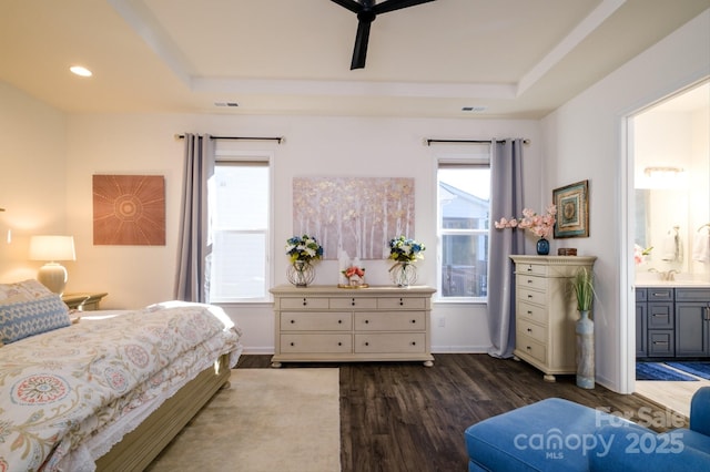 bedroom featuring dark wood-type flooring, ensuite bathroom, and a tray ceiling