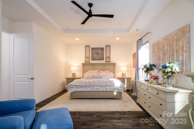 bedroom with ceiling fan, dark hardwood / wood-style floors, and a raised ceiling