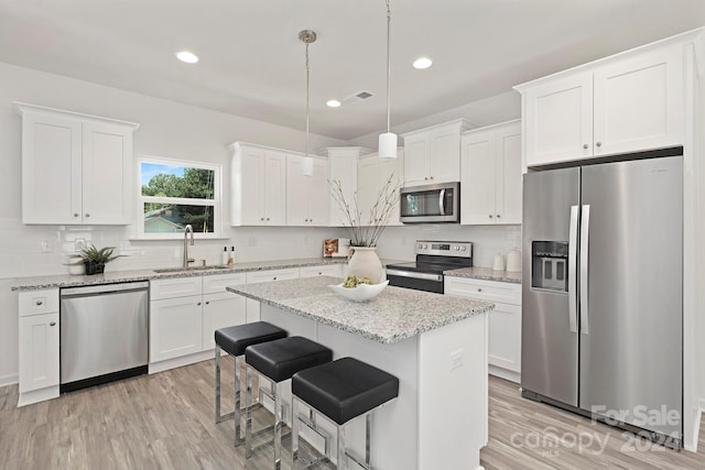 kitchen featuring white cabinetry, stainless steel appliances, sink, and hanging light fixtures