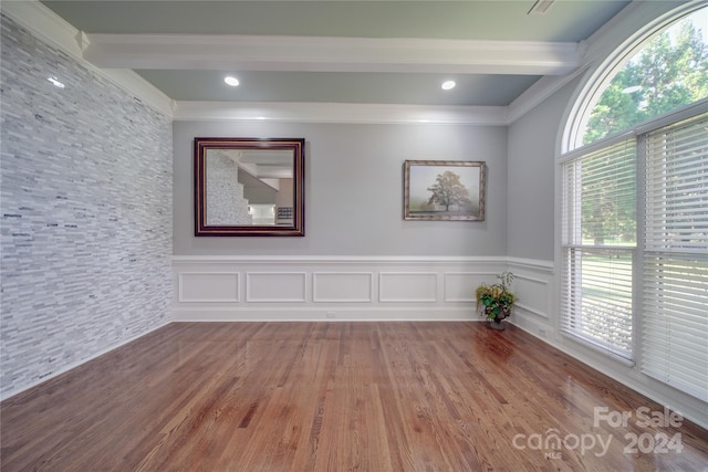 unfurnished room featuring ornamental molding, a healthy amount of sunlight, hardwood / wood-style flooring, and beamed ceiling