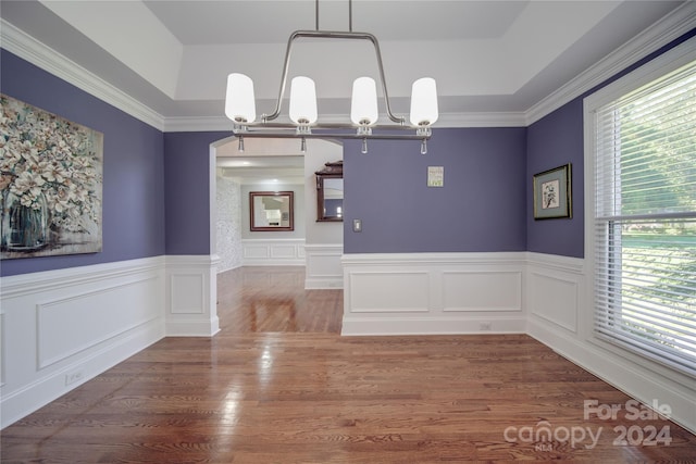 unfurnished dining area with hardwood / wood-style floors, crown molding, and a chandelier