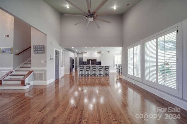 unfurnished living room with ceiling fan, high vaulted ceiling, and hardwood / wood-style floors