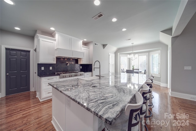 kitchen featuring a spacious island, stainless steel gas cooktop, white cabinetry, and wood-type flooring