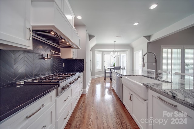 kitchen with decorative backsplash, white cabinetry, light stone countertops, dark hardwood / wood-style floors, and stainless steel appliances