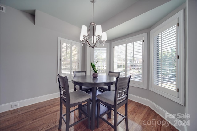 dining area featuring a wealth of natural light, dark hardwood / wood-style floors, and an inviting chandelier