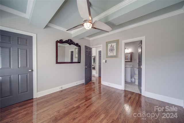 unfurnished bedroom with ensuite bathroom, beam ceiling, ceiling fan, dark wood-type flooring, and crown molding