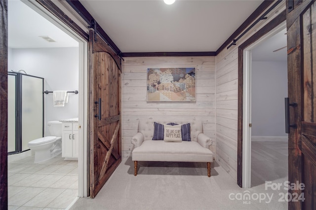 interior space with a barn door, light colored carpet, and wooden walls