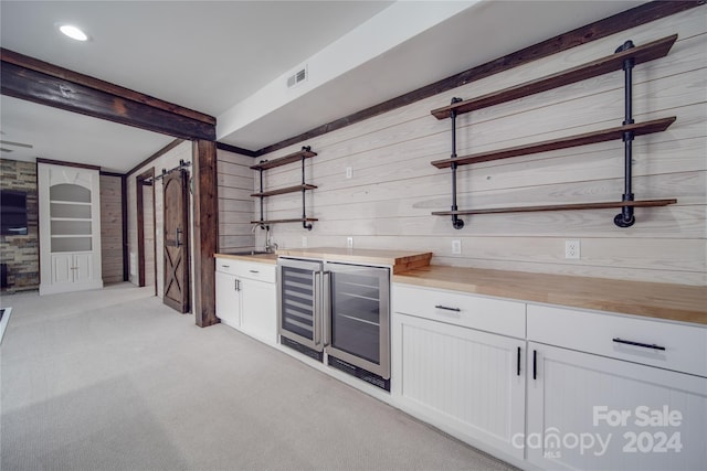 bar with white cabinetry, wood counters, light colored carpet, and beverage cooler