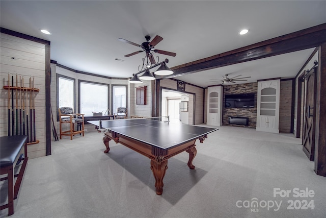 rec room featuring light colored carpet, beamed ceiling, a fireplace, and ceiling fan