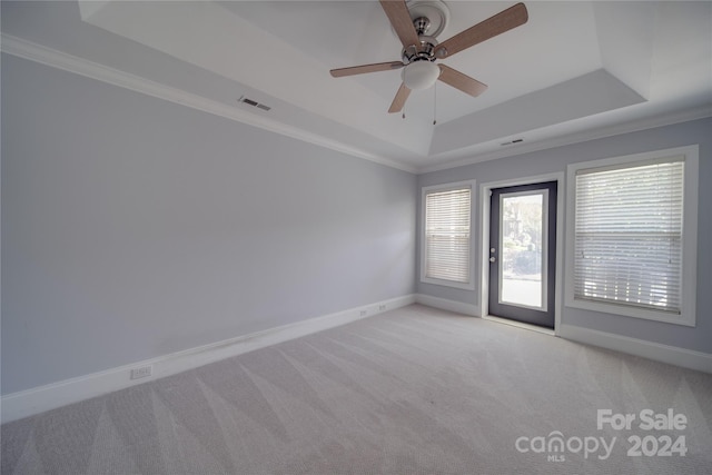 carpeted spare room with ornamental molding, a tray ceiling, and ceiling fan