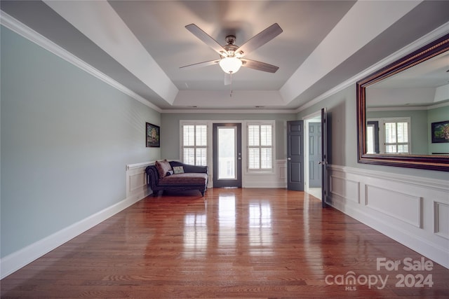 foyer entrance with ceiling fan, wood-type flooring, a tray ceiling, and ornamental molding