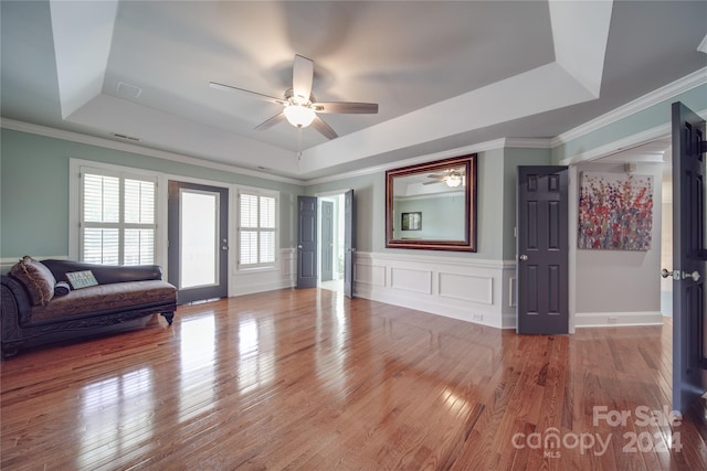 unfurnished living room with ornamental molding, hardwood / wood-style floors, a tray ceiling, and ceiling fan