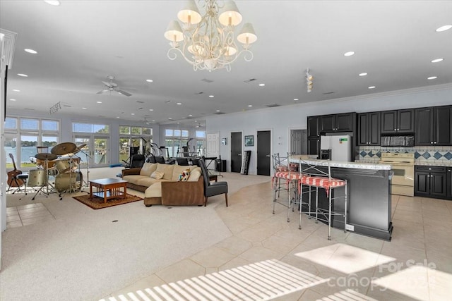 tiled living room featuring a water view, crown molding, and ceiling fan with notable chandelier