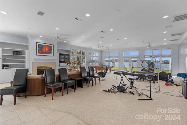 interior space with ceiling fan, a tile fireplace, a water view, and light tile patterned floors