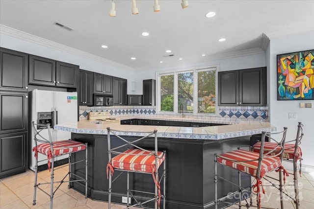 kitchen featuring ornamental molding, light tile patterned flooring, a kitchen bar, white appliances, and tasteful backsplash