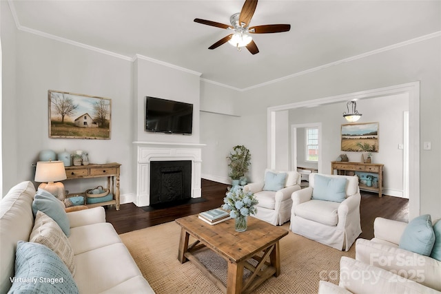 living area with a fireplace with flush hearth, a ceiling fan, baseboards, ornamental molding, and dark wood-style floors