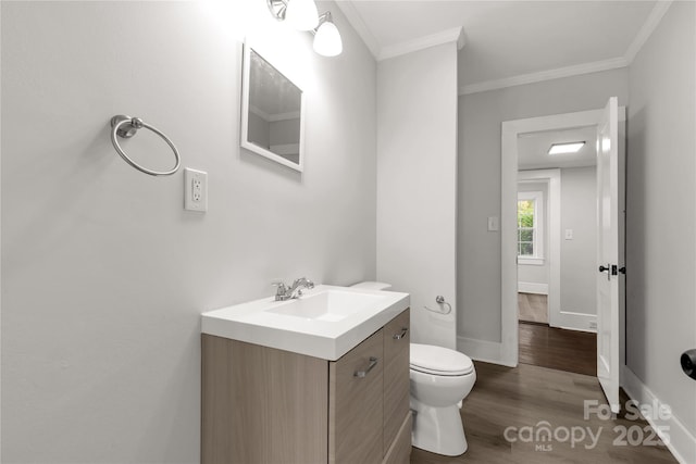 bathroom featuring hardwood / wood-style flooring, vanity, crown molding, and toilet