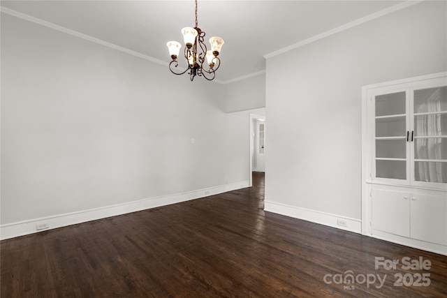 empty room featuring a chandelier, ornamental molding, dark wood-type flooring, and baseboards