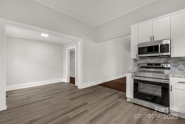 kitchen featuring stainless steel appliances, wood finished floors, white cabinetry, baseboards, and backsplash