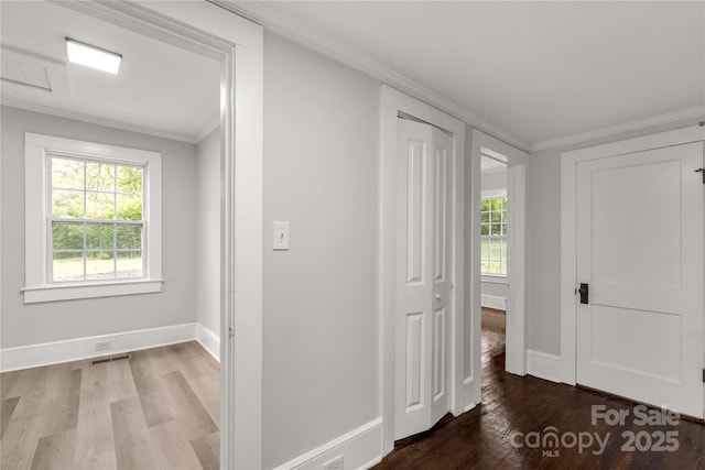 hallway with baseboards, light wood-type flooring, plenty of natural light, and crown molding