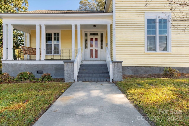 entrance to property with a yard and covered porch