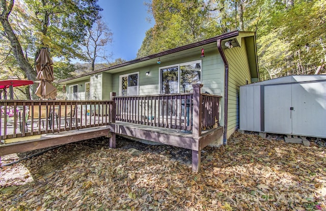 back of house with a wooden deck and a shed