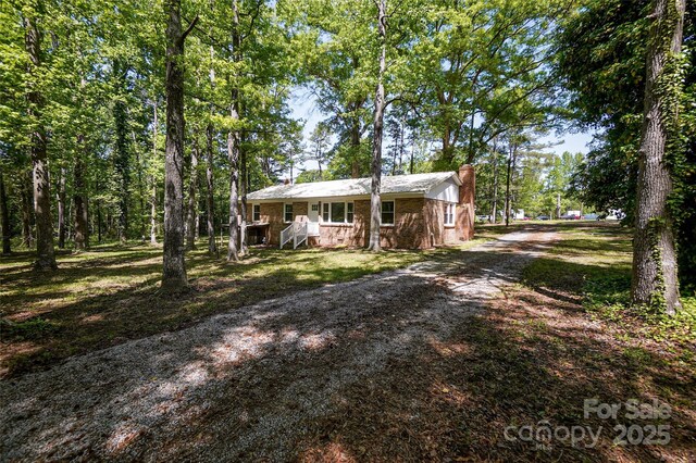 view of front of property with a chimney and dirt driveway
