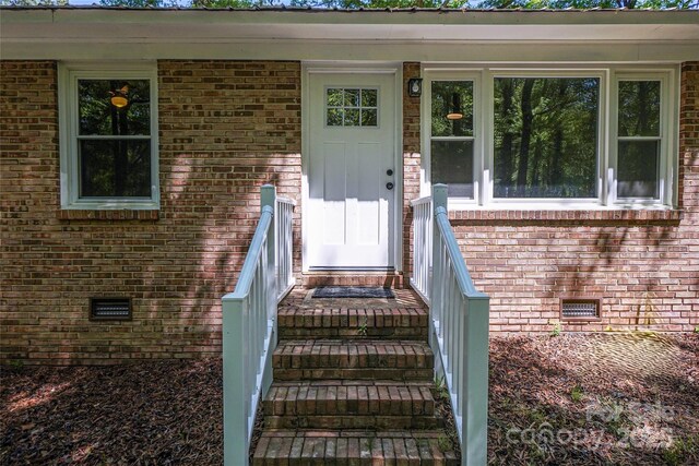 view of exterior entry featuring crawl space and brick siding