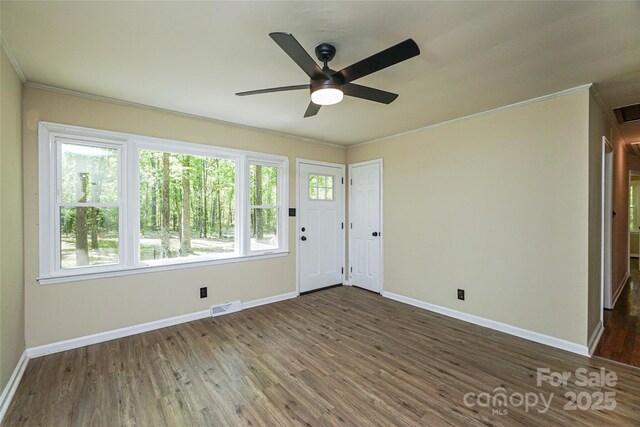 empty room featuring ornamental molding, baseboards, dark wood-style floors, and ceiling fan