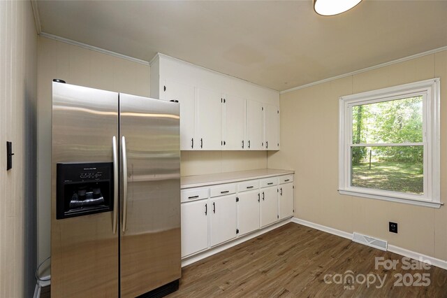 kitchen featuring stainless steel refrigerator with ice dispenser, dark wood finished floors, crown molding, white cabinetry, and light countertops
