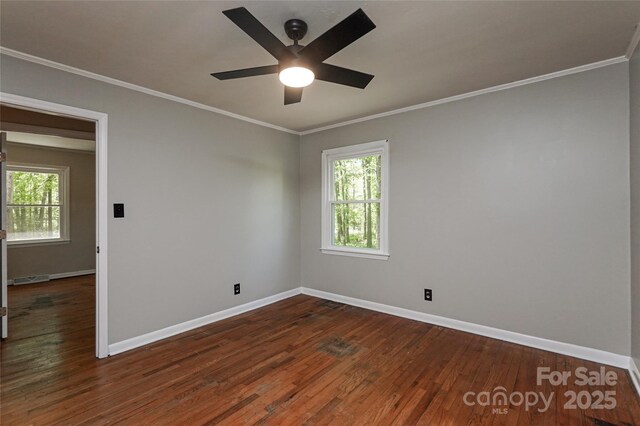 spare room with dark wood-type flooring, baseboards, healthy amount of natural light, and ornamental molding