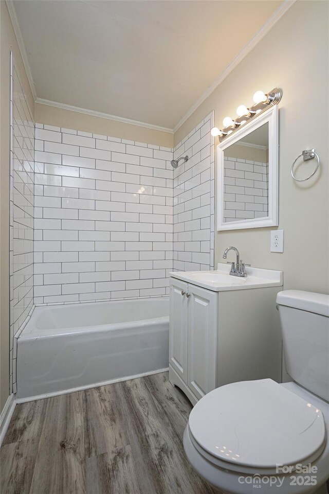 full bath with toilet, ornamental molding, wood finished floors, shower / tub combination, and vanity