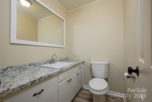 bathroom featuring wood finished floors, toilet, crown molding, vanity, and baseboards