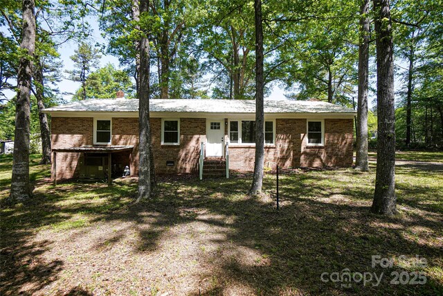 view of front of house with crawl space, brick siding, entry steps, and a chimney