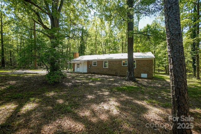 rear view of property with a chimney, crawl space, and brick siding