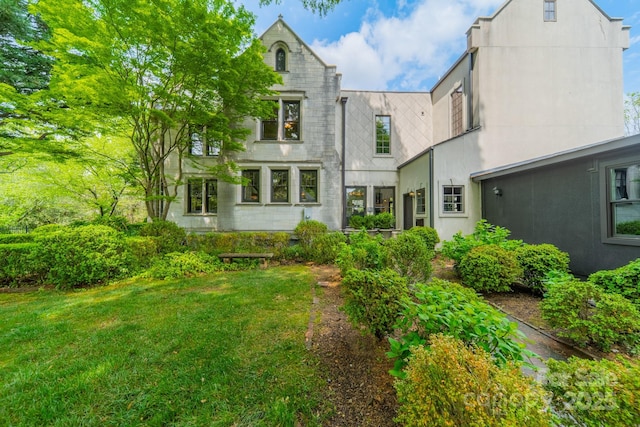 back of property featuring a yard and stucco siding