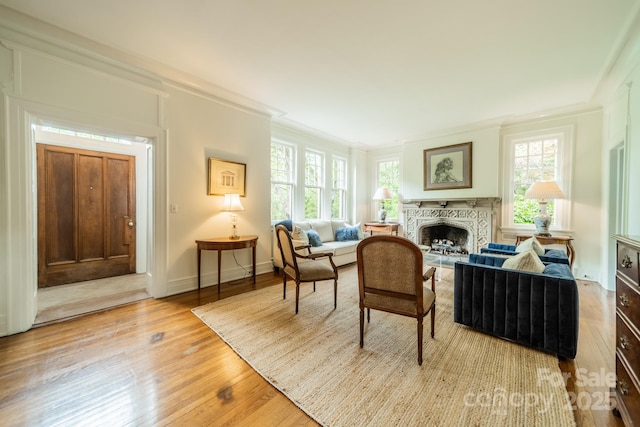 sitting room with light wood-style floors, baseboards, a fireplace, and ornamental molding