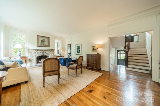 living room with crown molding, stairs, wood finished floors, and a high end fireplace