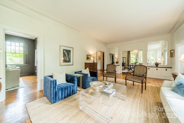 living area with ornamental molding and light wood-style flooring
