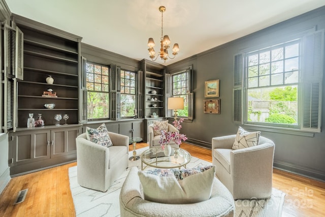 sitting room with a chandelier, wood finished floors, visible vents, and baseboards