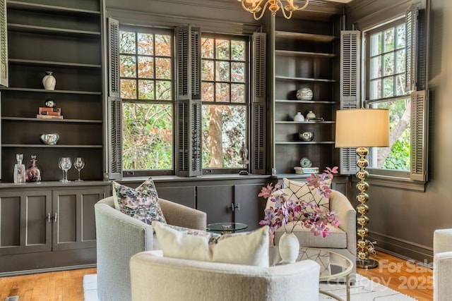 living area with baseboards, a notable chandelier, and light wood finished floors