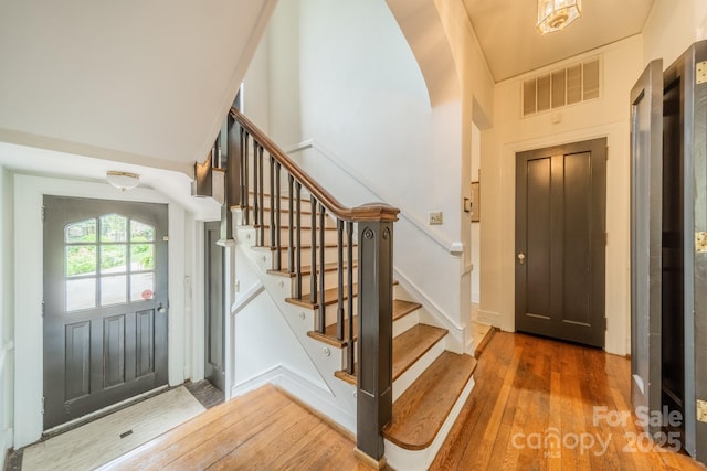 foyer entrance with stairway, wood-type flooring, visible vents, and elevator