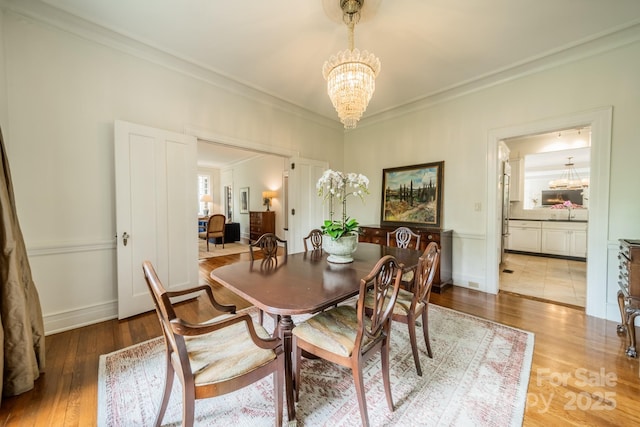 dining room featuring wood finished floors, crown molding, and an inviting chandelier