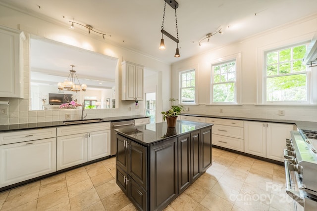kitchen featuring tasteful backsplash, appliances with stainless steel finishes, ornamental molding, decorative light fixtures, and a sink