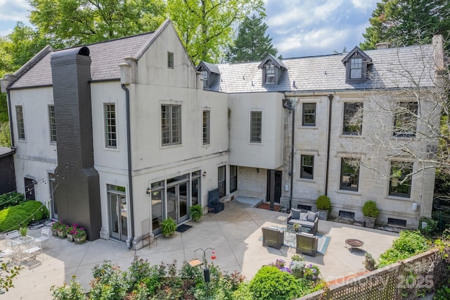 rear view of house featuring a high end roof, stucco siding, a patio area, and an outdoor hangout area
