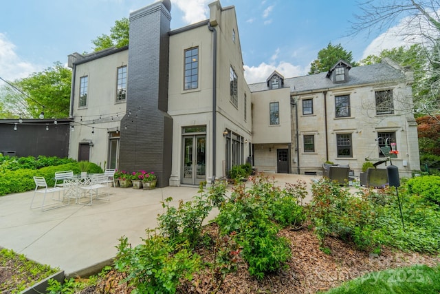 rear view of property with french doors, a patio, a chimney, and stucco siding