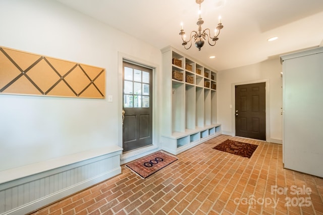 mudroom with brick floor, an inviting chandelier, and recessed lighting
