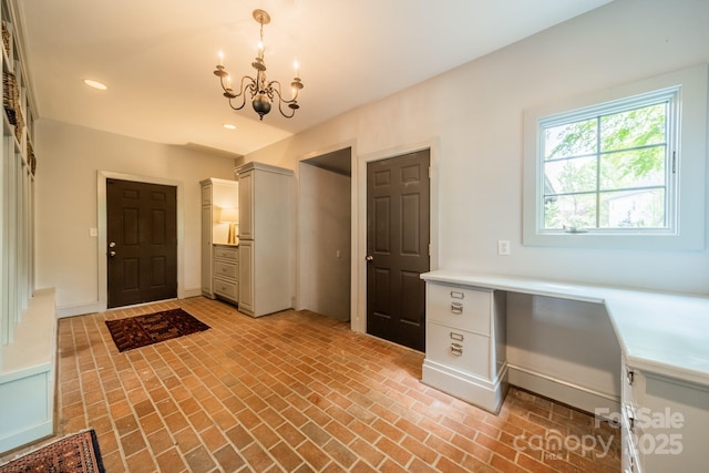 foyer entrance featuring brick floor, built in desk, a notable chandelier, and recessed lighting